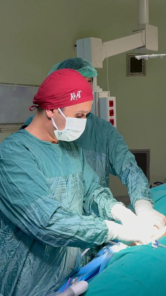 Op. Dr. Kayhan Tarım ameliyathanede, cerrahi önlük ve maskeyle çalışırken.